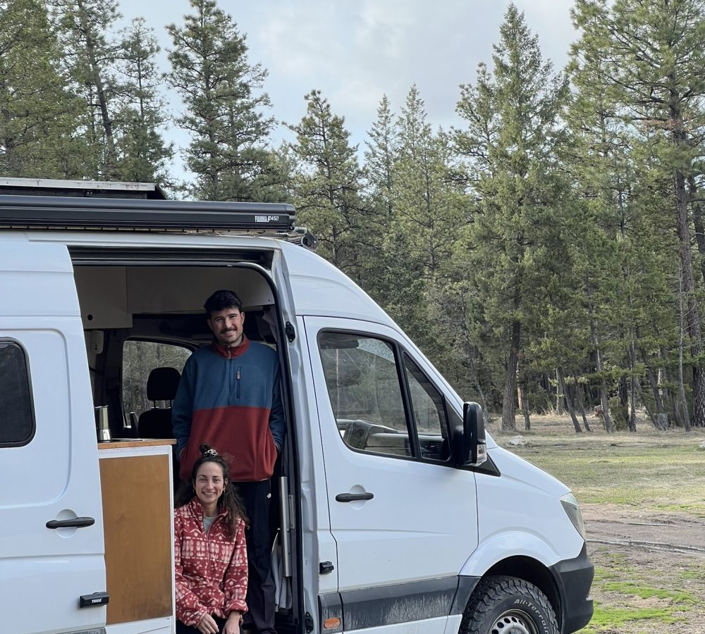 Pareja vanlife de CastleVans delante de su furgoneta camper